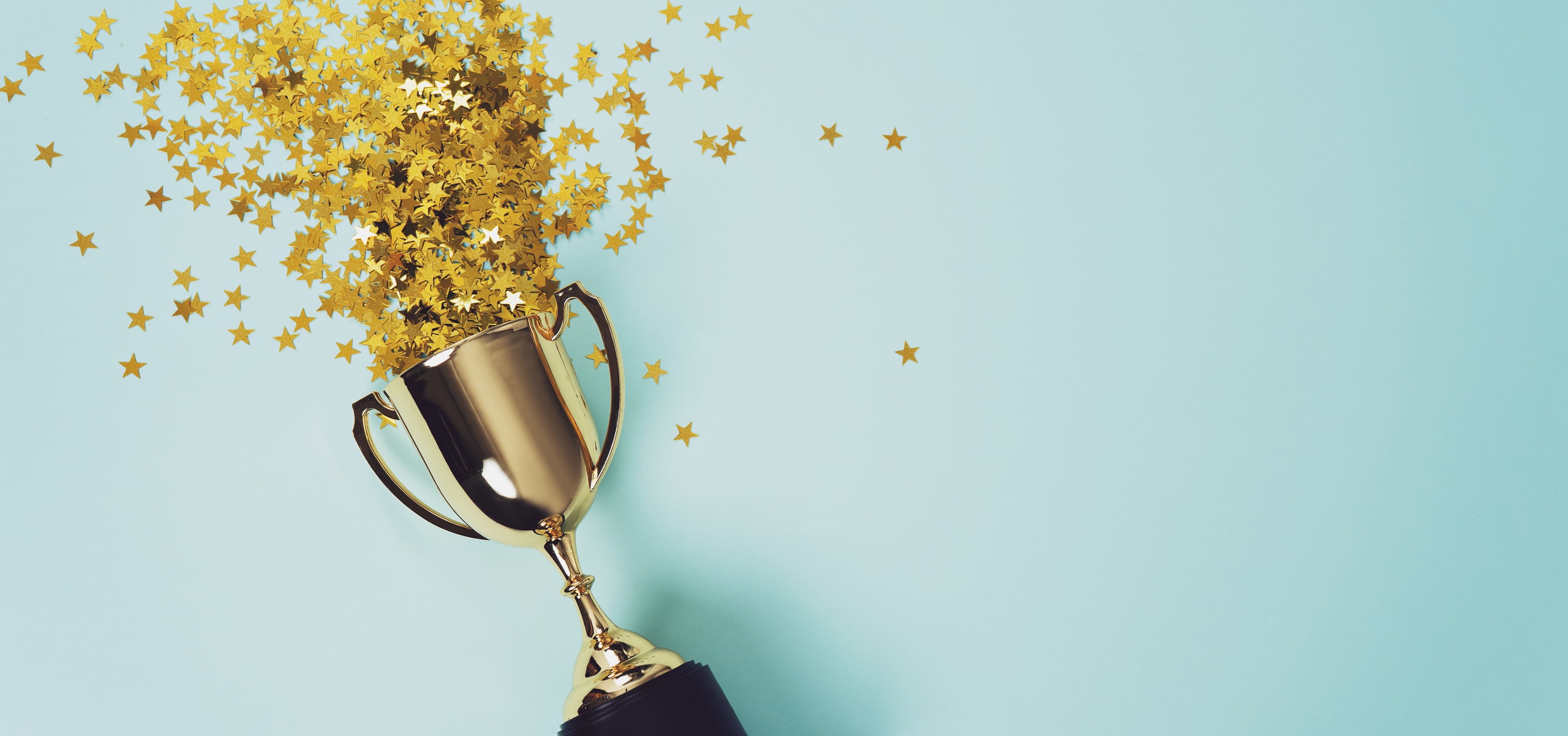 A golden trophy cup with golden stars spilling out of it on a blue background.